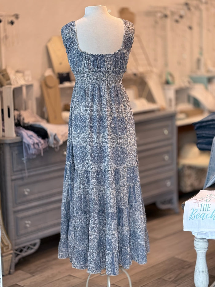 A blue and ivory paisley print maxi dress with ruffled cap sleeves and a smocked waist on a mannequin.