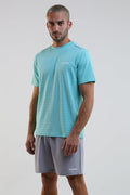 Man wearing a light blue t-shirt and gray shorts with a brand logo on a white background