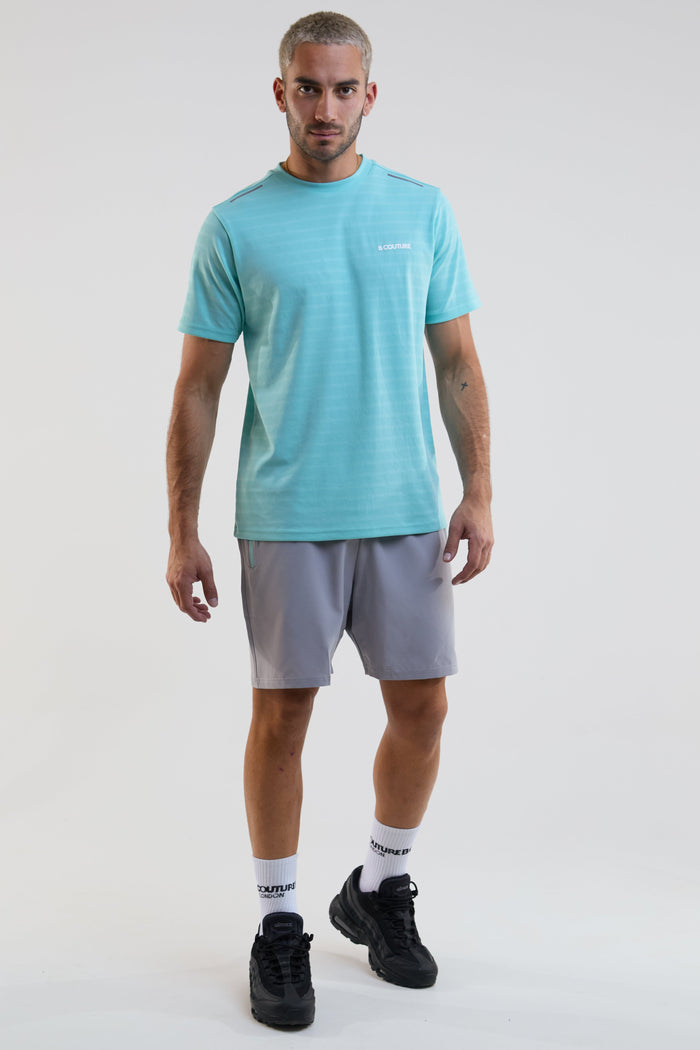 Man wearing a light blue t-shirt and gray shorts on a white background