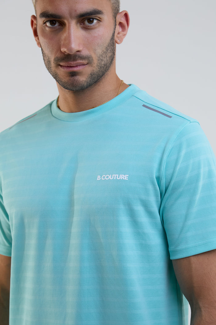 Man wearing a light blue t-shirt with a brand logo on a plain background