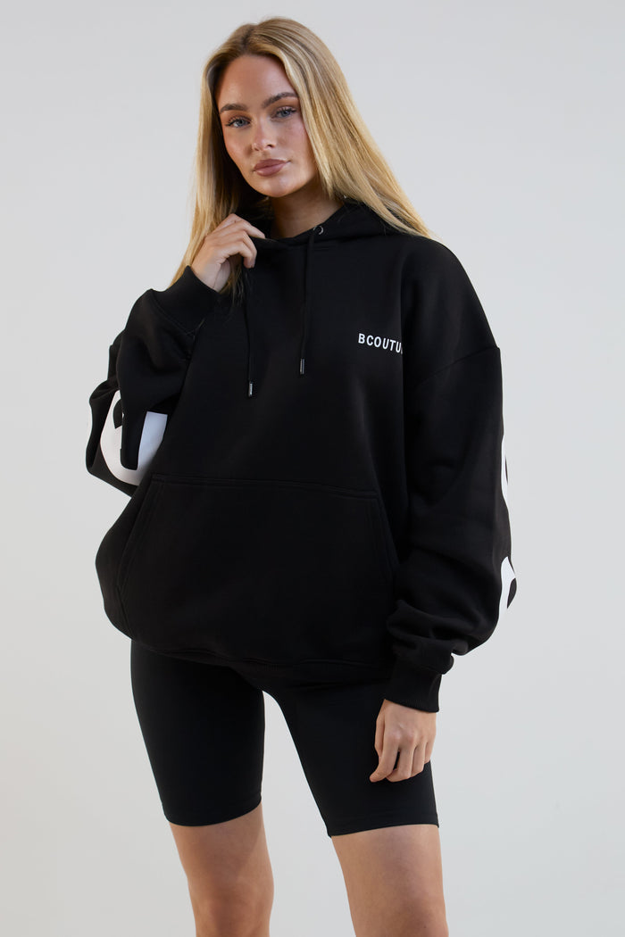Person wearing a black hoodie with 'B COUTURE' branding on a plain background