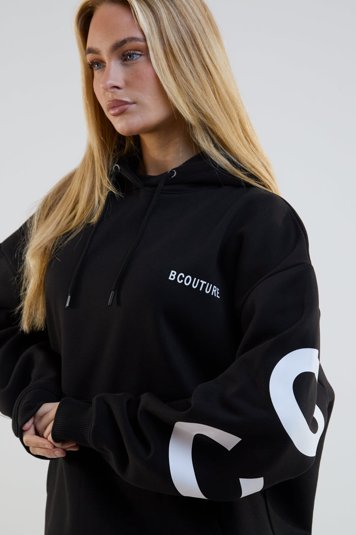 Person wearing a black hoodie with 'BCouture' branding on a plain background