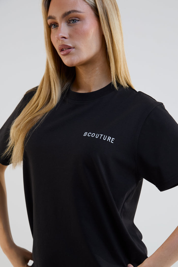 Woman wearing a black t-shirt with 'BCOUTURE' logo on a plain background
