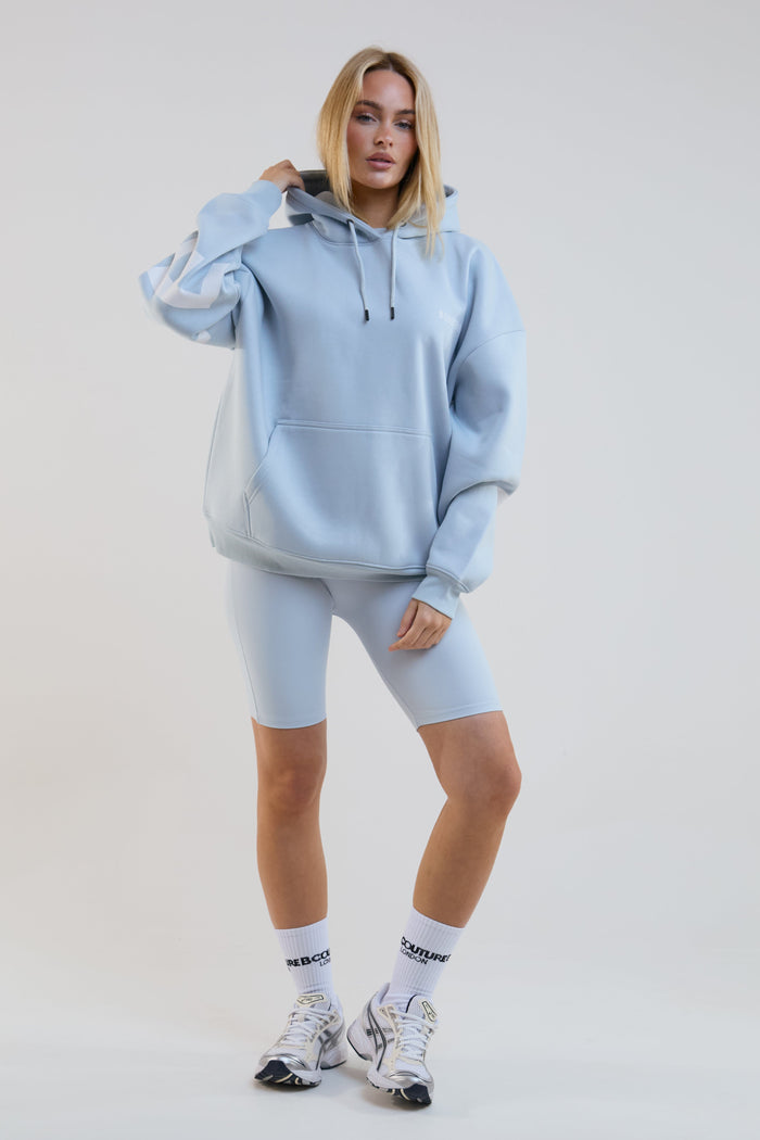 Person wearing a light blue hoodie and shorts set on a plain background