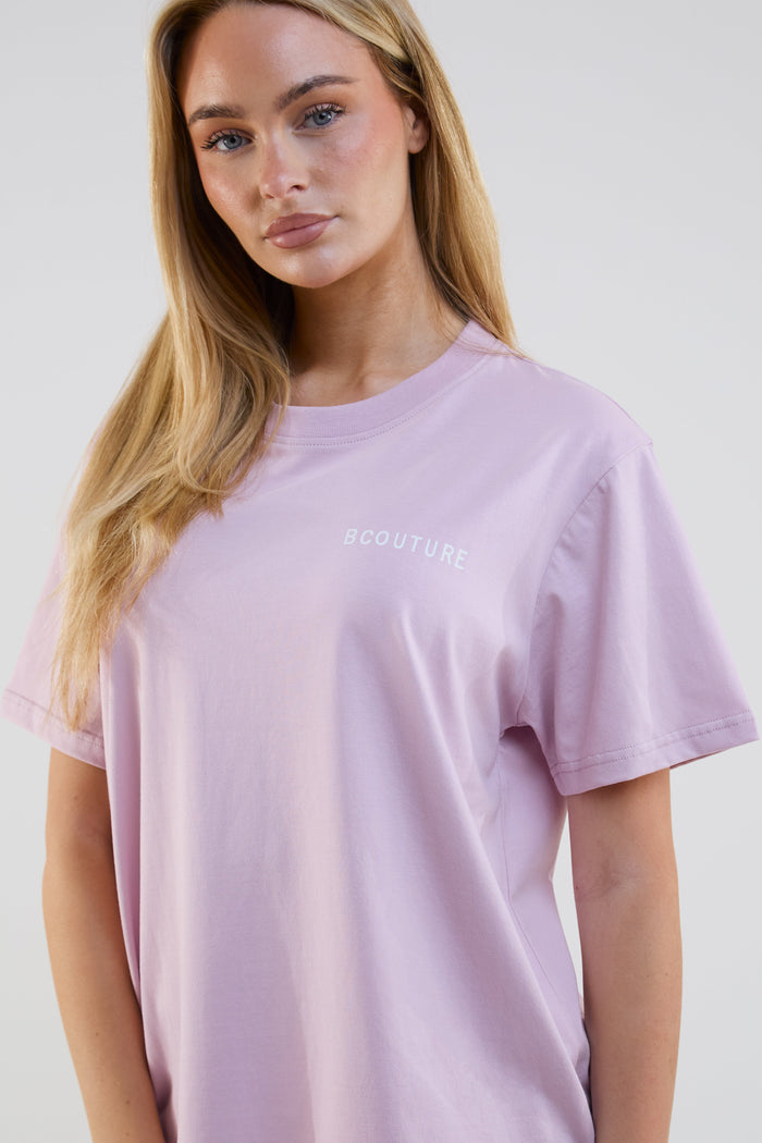 Woman wearing a light purple t-shirt with text on a plain background