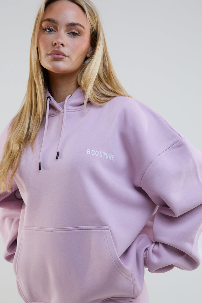 Person wearing a light purple hoodie with 'BCouture' branding on a plain background