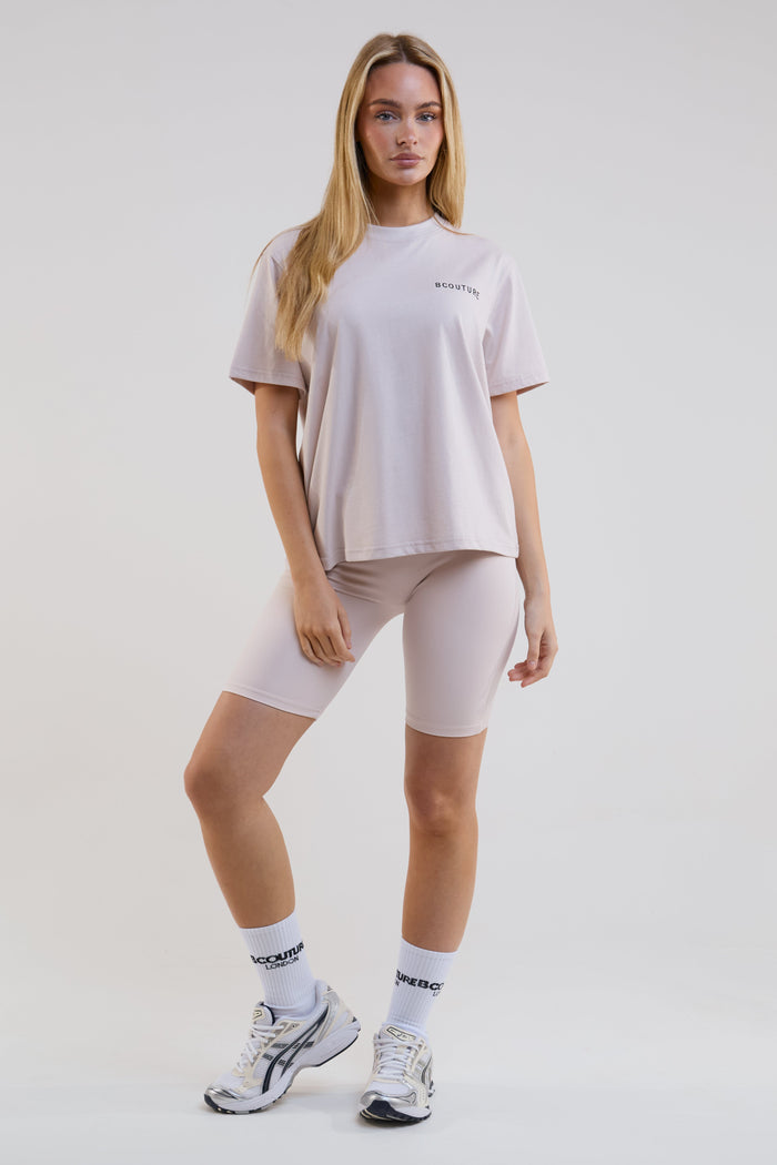 Woman wearing a beige t-shirt, shorts, and socks on a white background