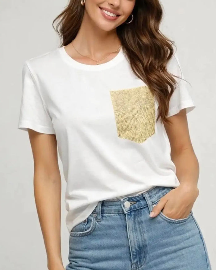 White short sleeve crew neck top with a gold sequin patch pocket, styled with blue jeans.