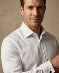 Man wearing a white dress shirt against a beige background