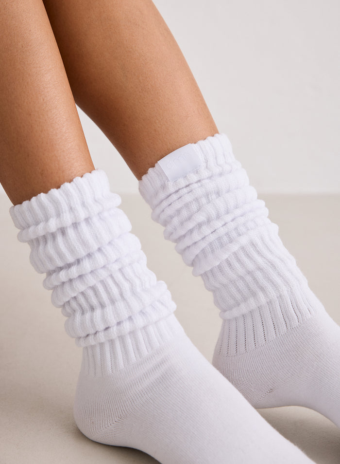 Lähikuva valkoisista aim'n Slouch Socks -sukista, jotka on rypytetty nilkoista.