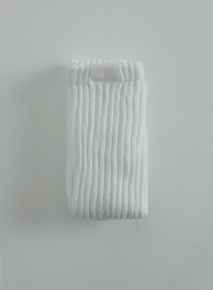 Valkoiset ribatut Slouch Socks taitettuna tuomaan esiin huomaamattoman aim'n-logomerkin.